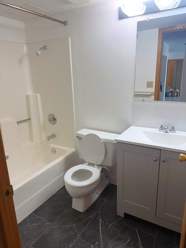 Cleaned bathroom with a grey vanity, mirror and dark tiled floor