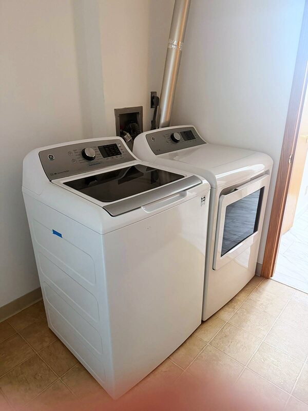 Clean laundry room with a white washer and dryer on tiled flooring